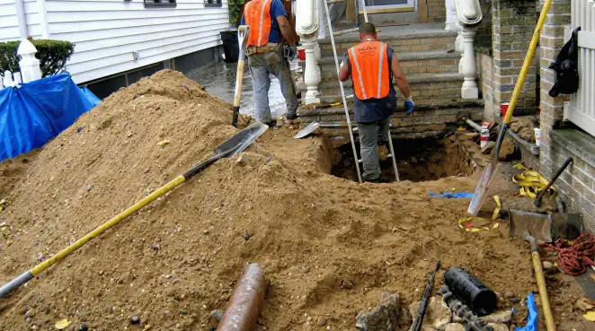 Contractors performing foundation protection and exterior drainage excavation near residential home steps in Wichita, KS